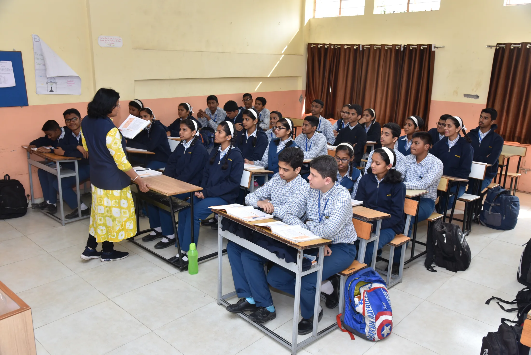 A teacher walks between the desks of her class